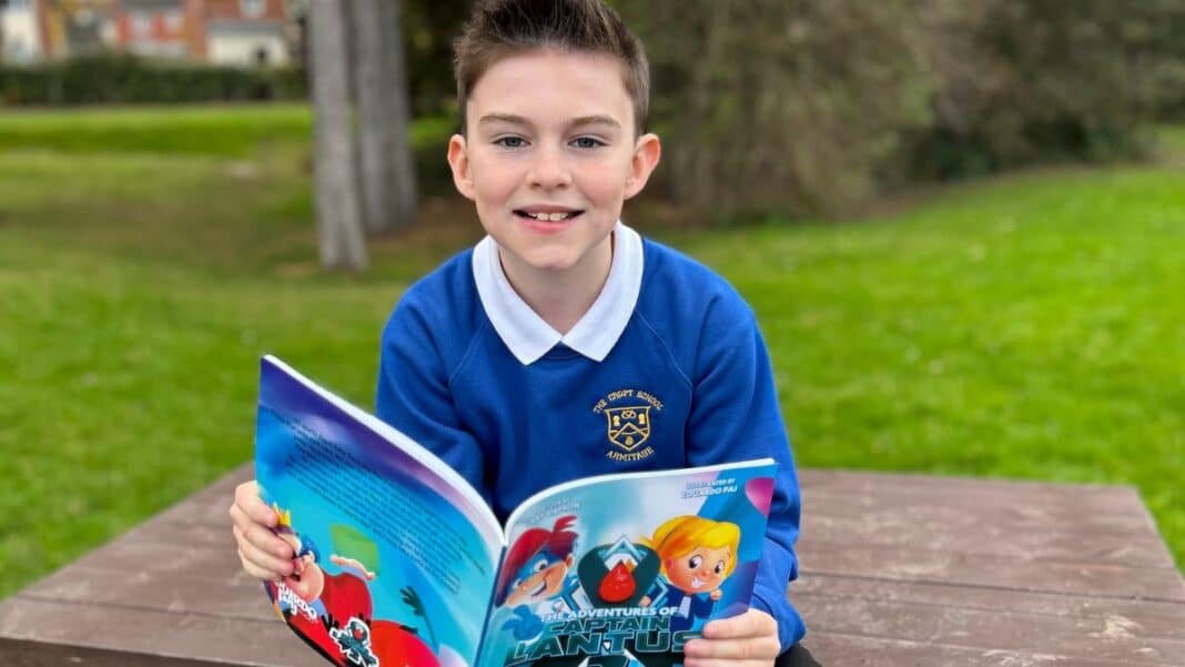 Boy with brown hair hols a copy of 'Captain Lantus' a superhero who has diabetes