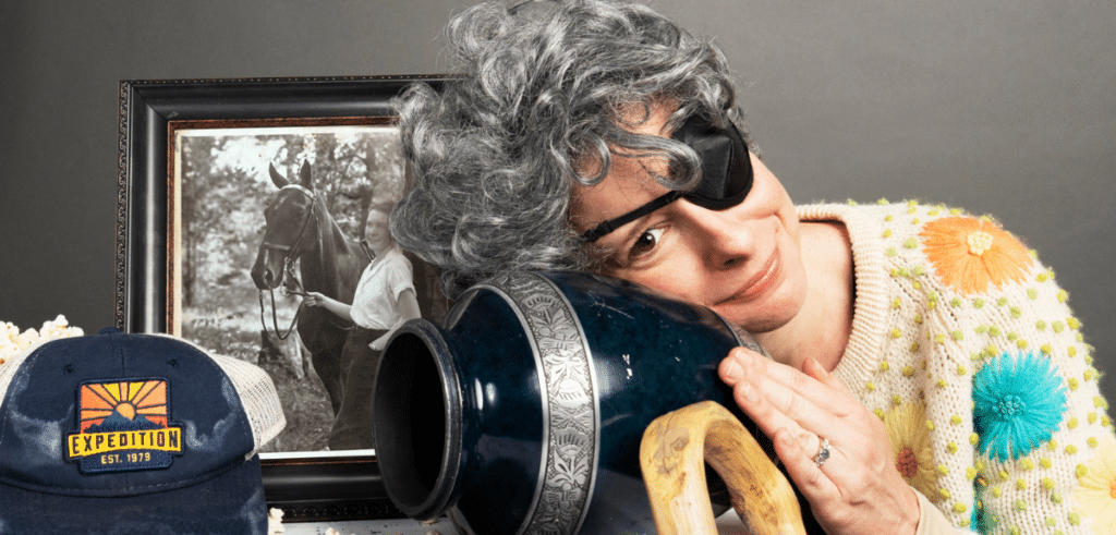 Julia VanderVeen is pictured dressed in costume as her Grandmother, wearing an eyepatch beside an empty urn and a family photograph