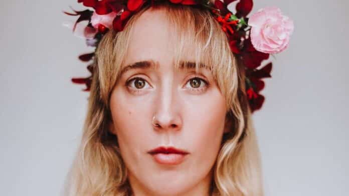 Kate-Lois Elliott wears a pink and red flower headband and the image has a 1970s feel.